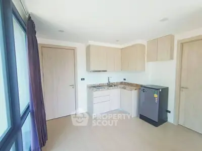 Modern kitchen with sleek cabinetry and compact fridge in bright apartment