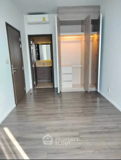 Spacious modern bedroom with built-in wardrobe and en-suite bathroom, featuring sleek wooden flooring.