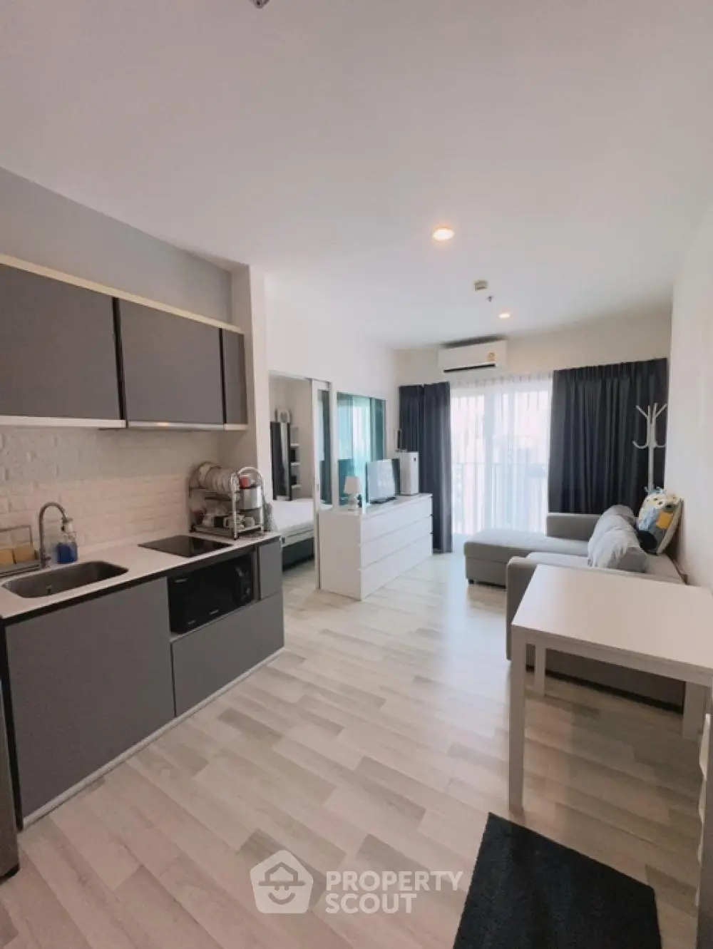 Modern open-plan living space with sleek kitchen and comfortable lounge area, featuring light wood flooring and contemporary furnishings.