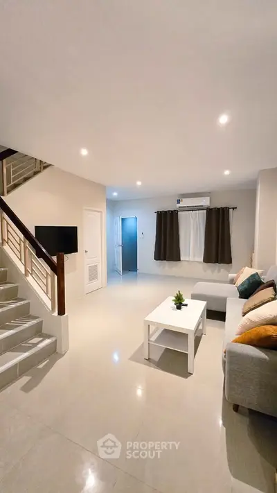 Spacious modern living room with sleek staircase and cozy seating area.