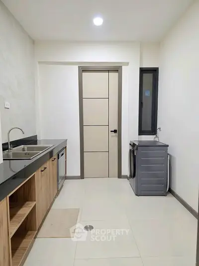 Modern kitchen with sleek cabinetry and washing machine in a contemporary apartment.