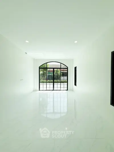 Spacious minimalist room with large window and marble flooring, perfect for modern living.