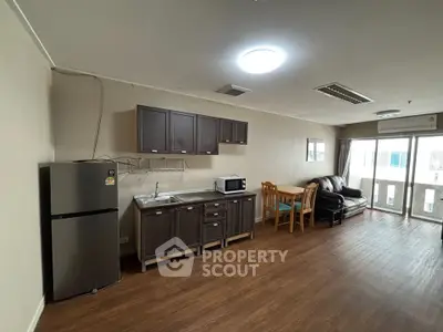Spacious open-plan living room with kitchen, dining area, and large windows for natural light.