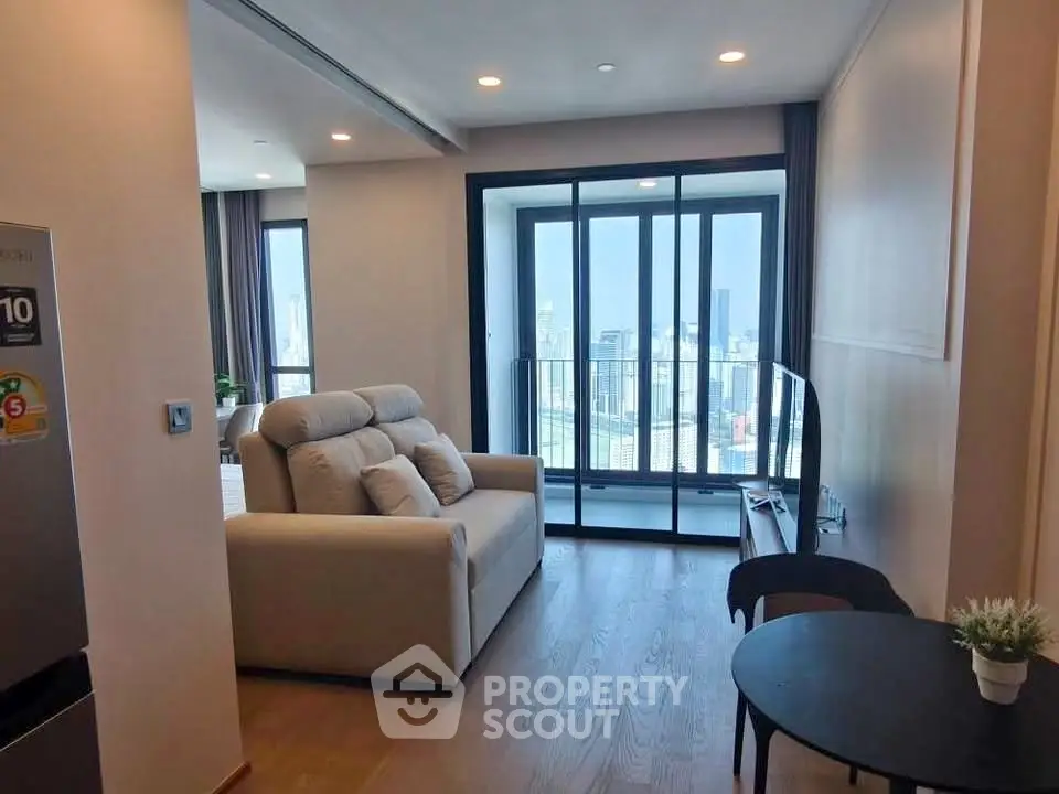 Modern living room with city view and cozy seating area in high-rise apartment.