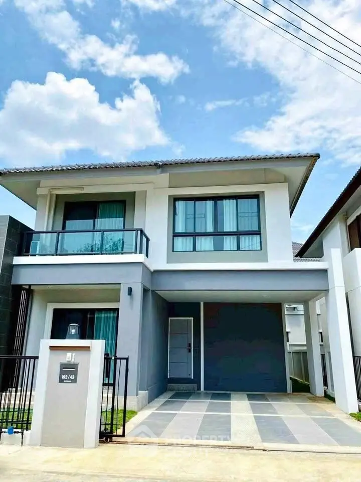 Modern two-story house with sleek design and spacious driveway under a clear blue sky.