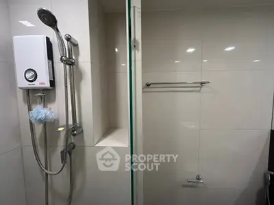 Modern bathroom with sleek shower and water heater, featuring minimalist design and neutral tiles.