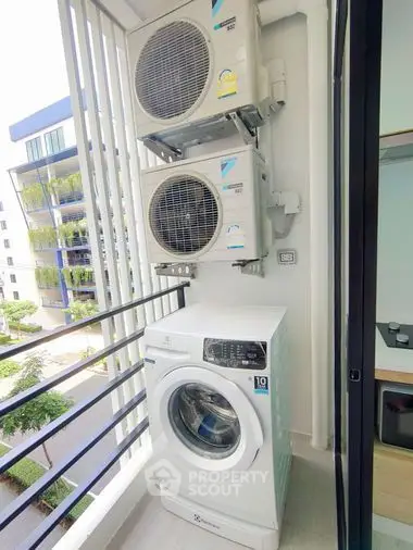 Modern balcony with washing machine and air conditioning units in urban apartment.