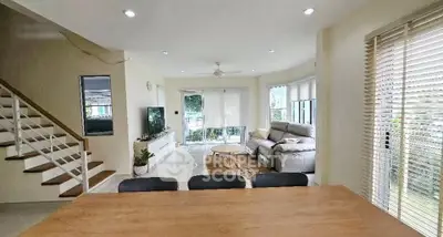 Spacious living room with modern decor and large windows offering natural light and garden view.