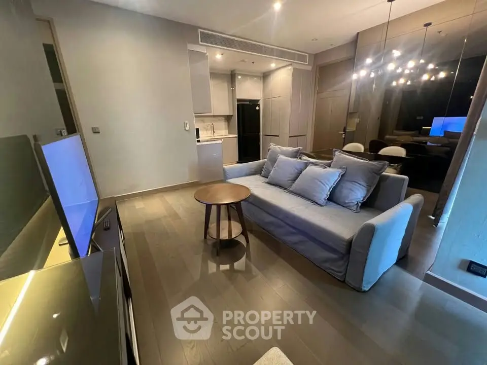 Modern living room with sleek design and open kitchen layout, featuring stylish lighting and comfortable seating.