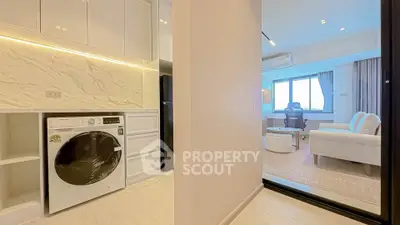 Modern apartment with open layout, featuring a sleek kitchen and cozy living area with natural light.