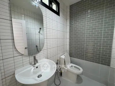 Modern bathroom with sleek white fixtures and stylish gray tile accent wall.