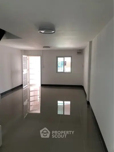 Spacious and bright interior room with glossy tiled flooring and ample natural light.