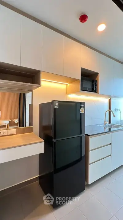 Modern kitchen with sleek cabinetry and black refrigerator in stylish apartment