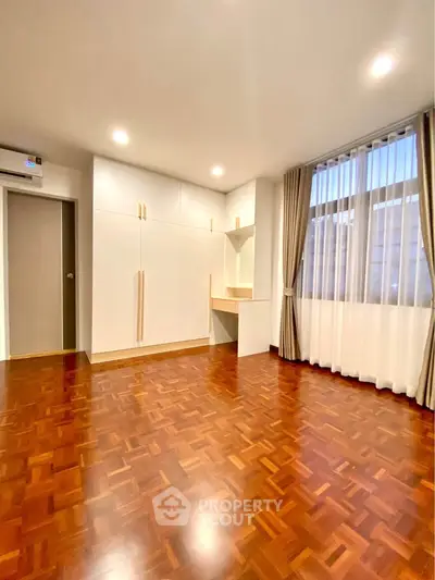 Spacious bedroom with elegant parquet flooring and built-in wardrobe