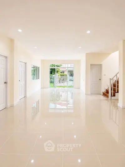 Spacious open-plan living room with glossy tile flooring and garden view.