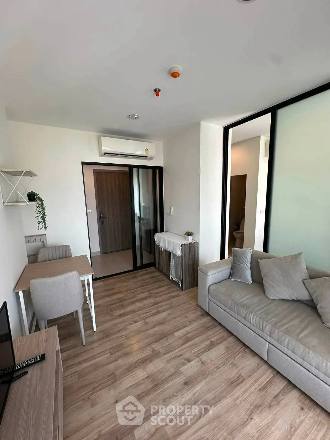 Modern living room with wooden flooring, cozy sofa, and dining area in a stylish apartment.