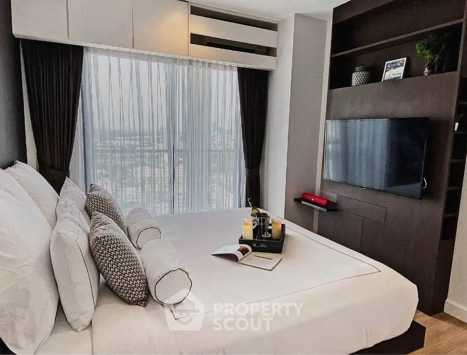 Luxurious bedroom with city view, modern decor, and wall-mounted TV in a high-rise apartment.