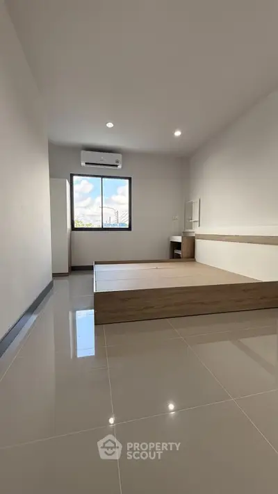 Spacious modern bedroom with sleek flooring and large window view.