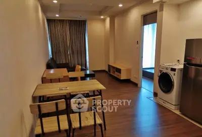 Modern apartment interior with dining area and washing machine, featuring wooden flooring and natural light.
