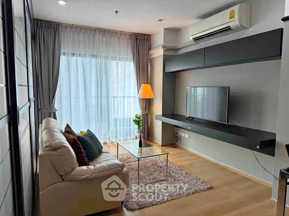 Modern living room with sleek design, featuring a cozy sofa, flat-screen TV, and large window for natural light.