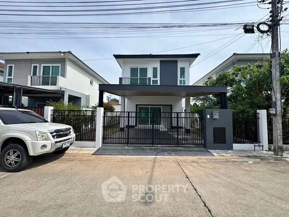 Modern two-story house with gated driveway and contemporary design in a suburban neighborhood.
