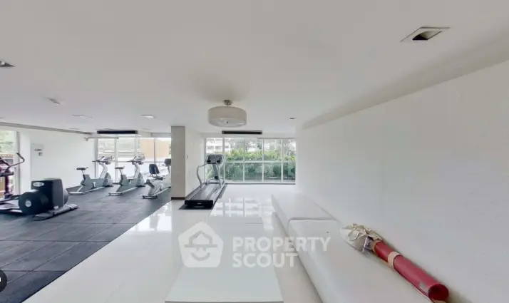 Spacious gym with modern equipment and large windows for natural light.