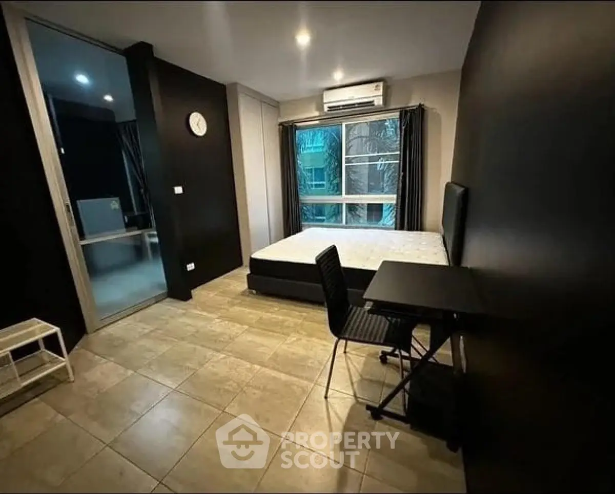 Modern bedroom with sleek black walls, large window, and minimalist furniture in urban apartment.