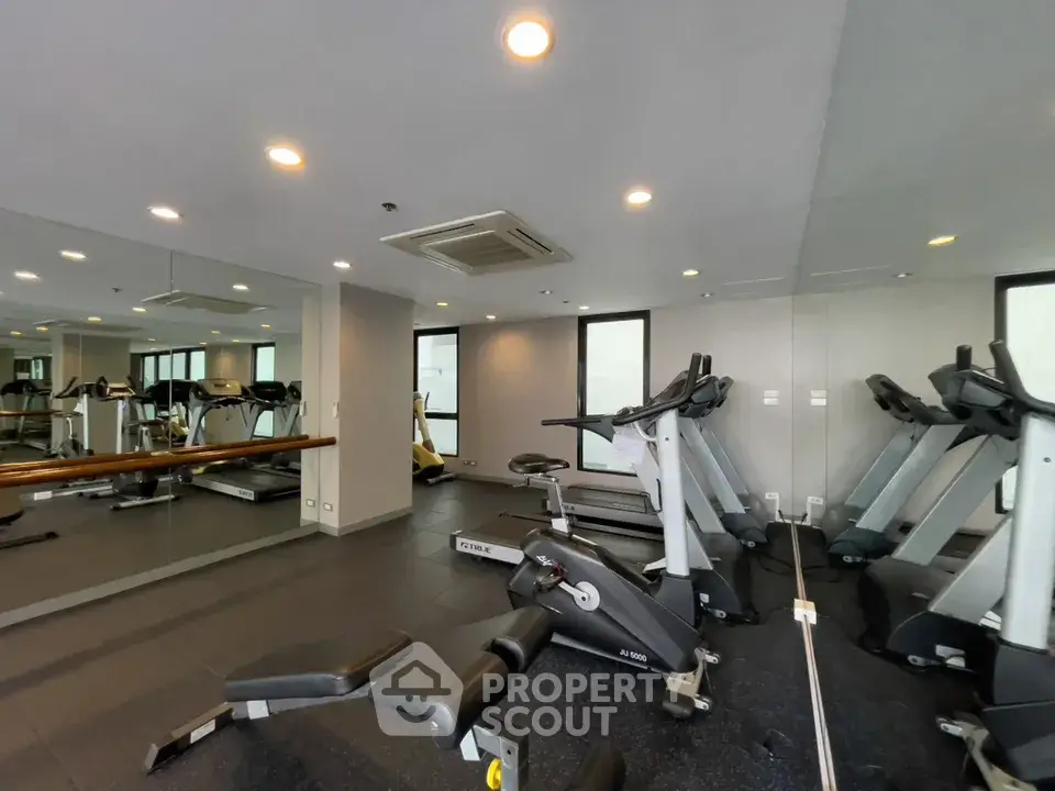 Modern gym with state-of-the-art fitness equipment and mirrored walls in a luxury apartment building.