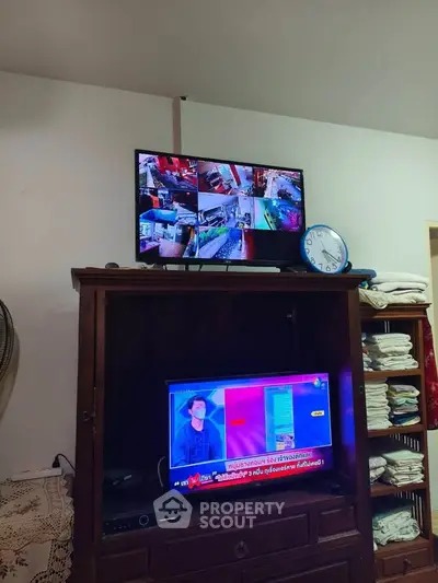 Cozy living room with TV setup and wooden cabinet, ideal for relaxation.
