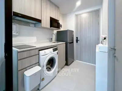Modern compact kitchen with washing machine and fridge in sleek apartment