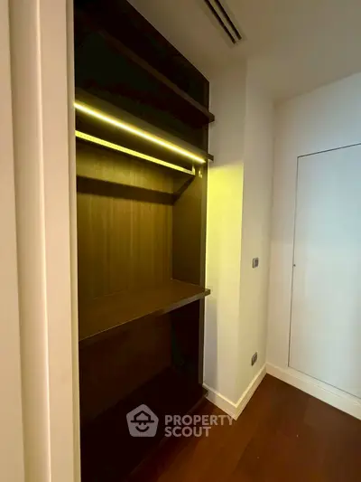 Spacious walk-in closet with modern lighting and wooden shelves in a luxury apartment.
