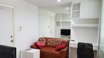 Cozy living room with brown leather sofa, modern desk, and wall-mounted TV in a compact apartment.