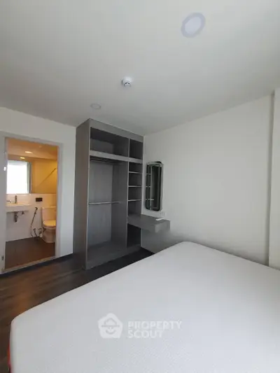 Modern bedroom with ensuite bathroom and built-in closet in a stylish apartment.