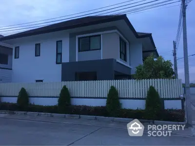 Modern two-story house with sleek design and fenced yard in suburban neighborhood.