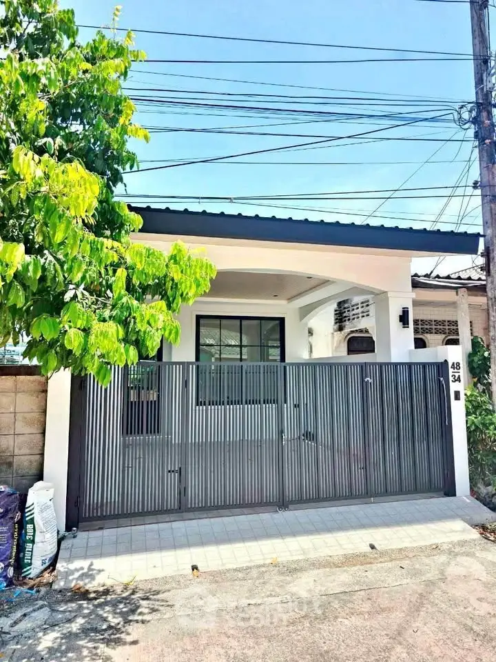 Charming single-story home with modern gate and lush greenery, perfect for cozy living.