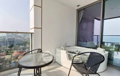 Luxurious balcony with stunning city and ocean view, featuring a cozy seating area and private jacuzzi.