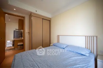 Cozy bedroom with wooden furniture and ensuite bathroom in modern apartment.