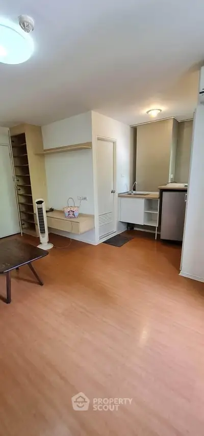 Modern studio apartment with wooden flooring and compact kitchen area.