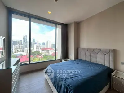 Modern bedroom with large window offering stunning city view in high-rise apartment.