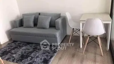 Cozy living room with modern gray sofa and sleek dining table set.