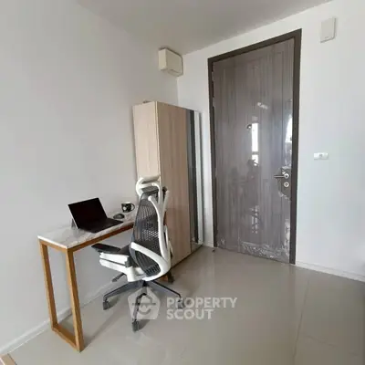 Modern study room with sleek desk and ergonomic chair in a minimalist apartment.