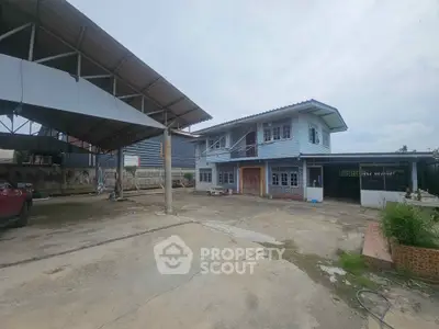 Spacious two-story house with large open yard and covered parking area.