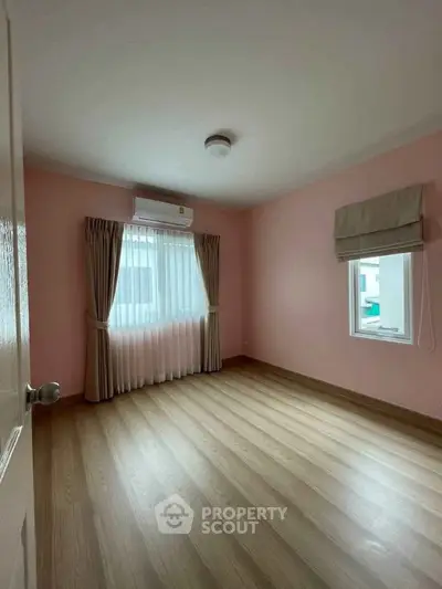 Spacious empty bedroom with wooden flooring and large window