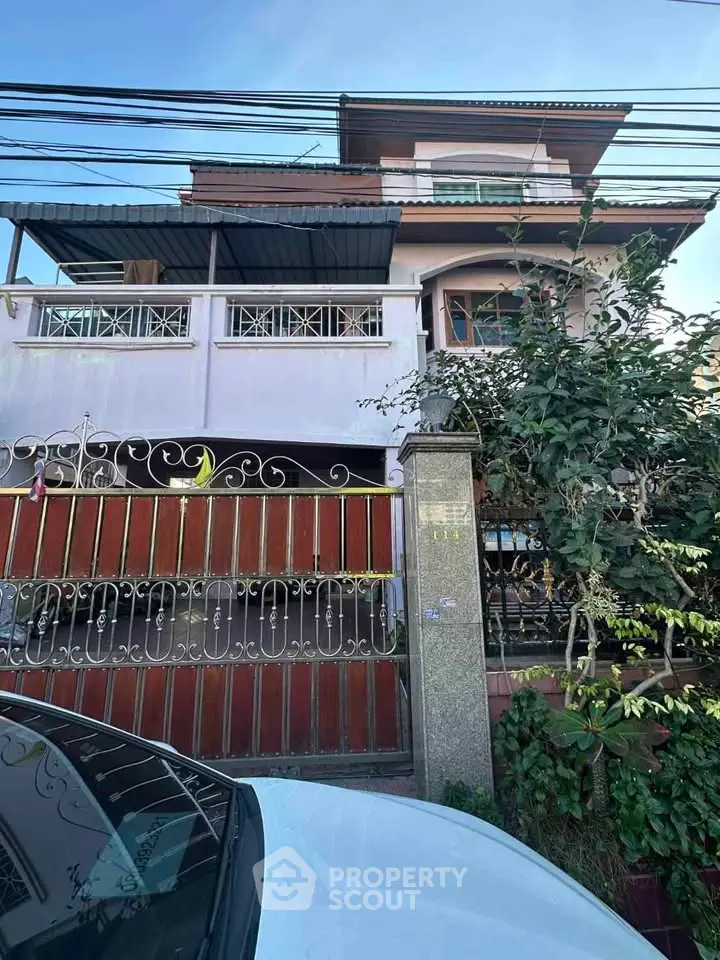 Charming multi-story house with gated entrance and lush greenery, perfect for family living.