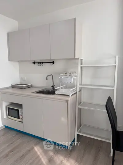 Modern compact kitchen with sleek cabinetry and built-in microwave, perfect for urban living.