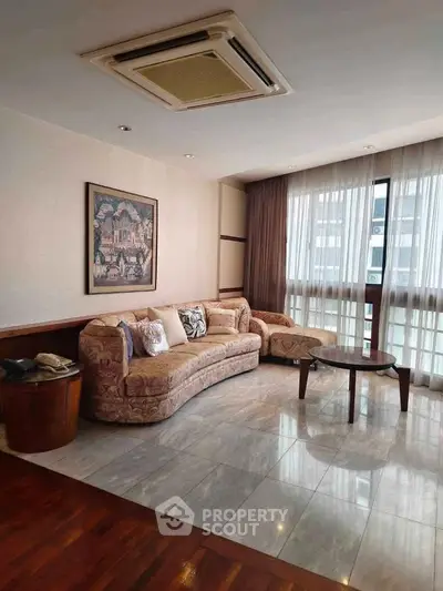 Spacious living room with elegant sofa and large window, perfect for relaxation and entertaining.