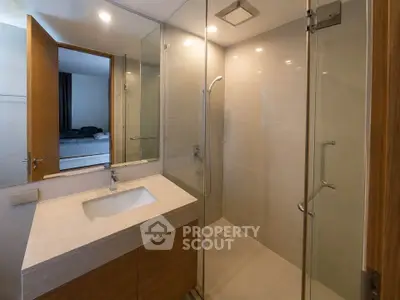 Modern bathroom with glass shower and sleek vanity in contemporary home.
