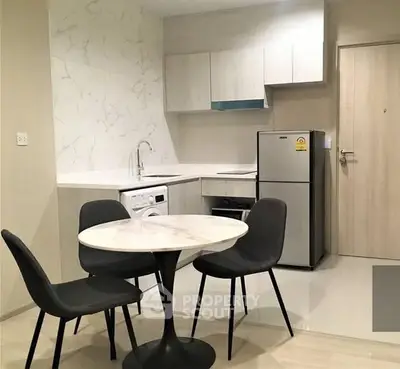 Modern kitchen with dining area, featuring sleek appliances and stylish furniture.