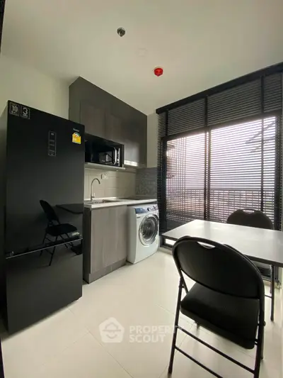 Modern kitchen with sleek appliances and large windows in a stylish apartment.