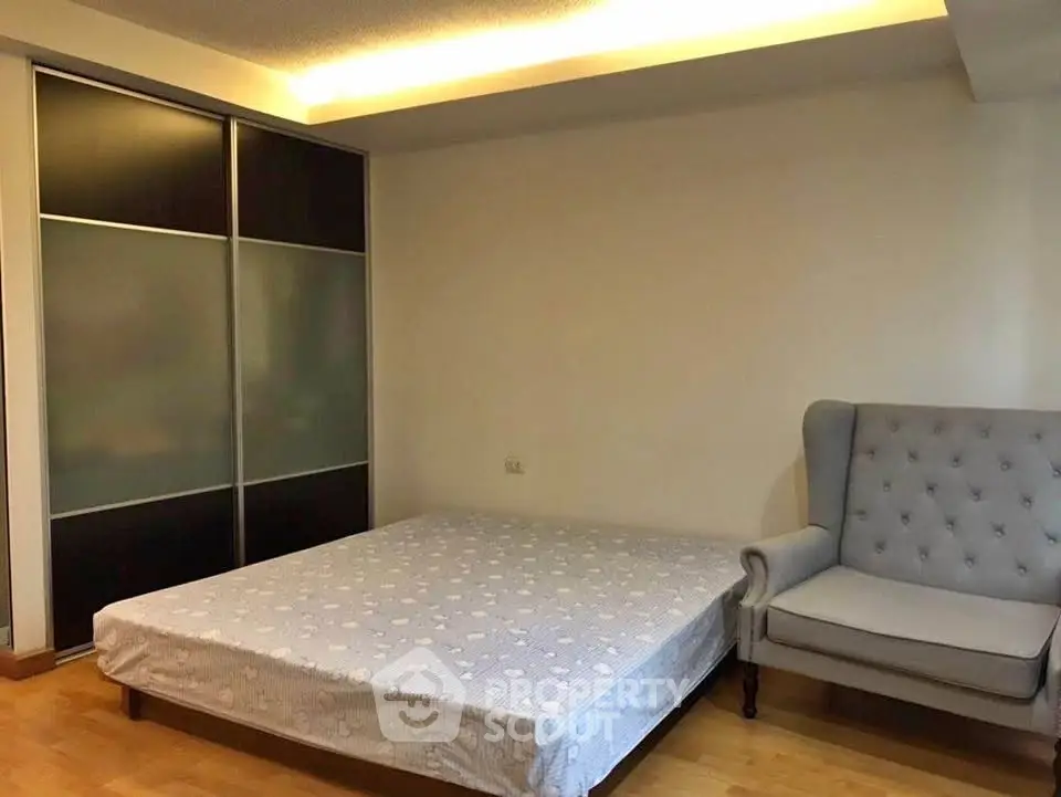 Spacious bedroom with modern sliding wardrobe and elegant armchair